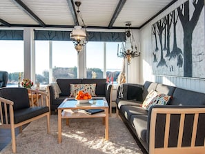 A cozy living room with a sofa, chairs, a coffee table, and a large window with a view.