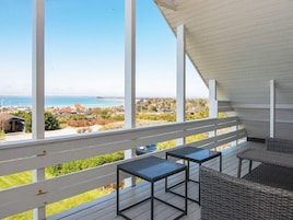 A balcony with a view of the sea and a residential area.