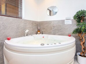 A large bathtub with a control panel, a potted plant, and a mirror on the wall. - Fantastic Holiday Home with Bay View near Knebel (Knebel)