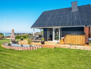 Une maison moderne dotée d’un patio, d’un espace salon extérieur et d’un jacuzzi.