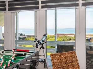 A room with a foosball table, a telescope, and a view of the ocean.