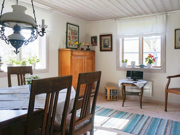 A dining area with wooden chairs, a table, a cabinet, and a television on a small table. - 5 Person Holiday Home in Kristinehamn (Kristinehamn)