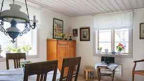 Uma sala de jantar com mobiliário de madeira, um candelabro e uma televisão sobre uma mesinha.