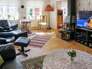 Un salon doté d’une cheminée, de canapés en cuir, d’un téléviseur et d’un coin repas avec une table et des chaises.