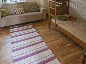A room with a wooden bunk bed, a sofa, and a striped area rug. - 5 Person Holiday Home in Kristinehamn (Kristinehamn)