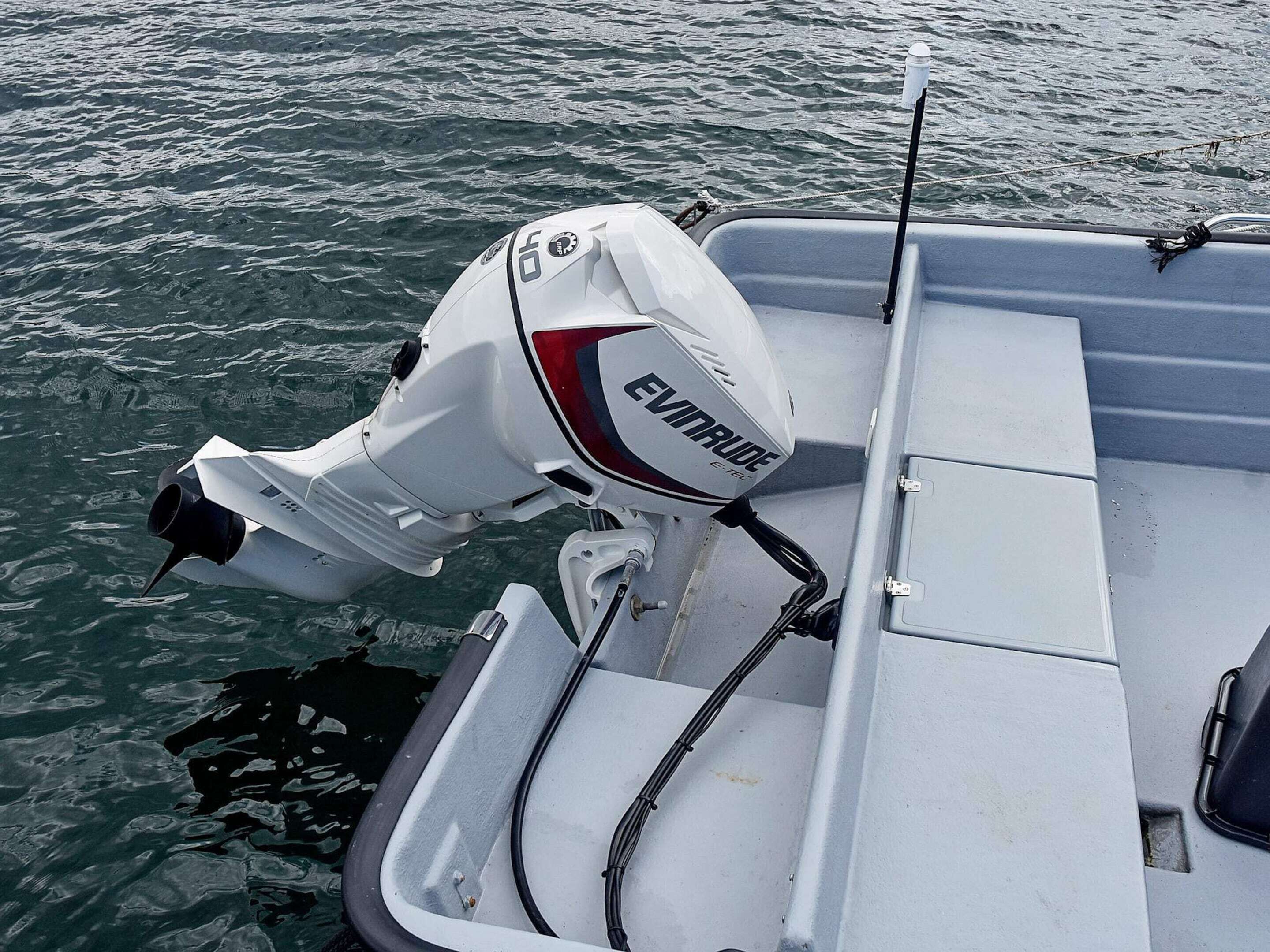 Una embarcació amb carena blanca, un motor fueraborda visible amb l'etiqueta 'EVINRUDE' i un penjol darrere.