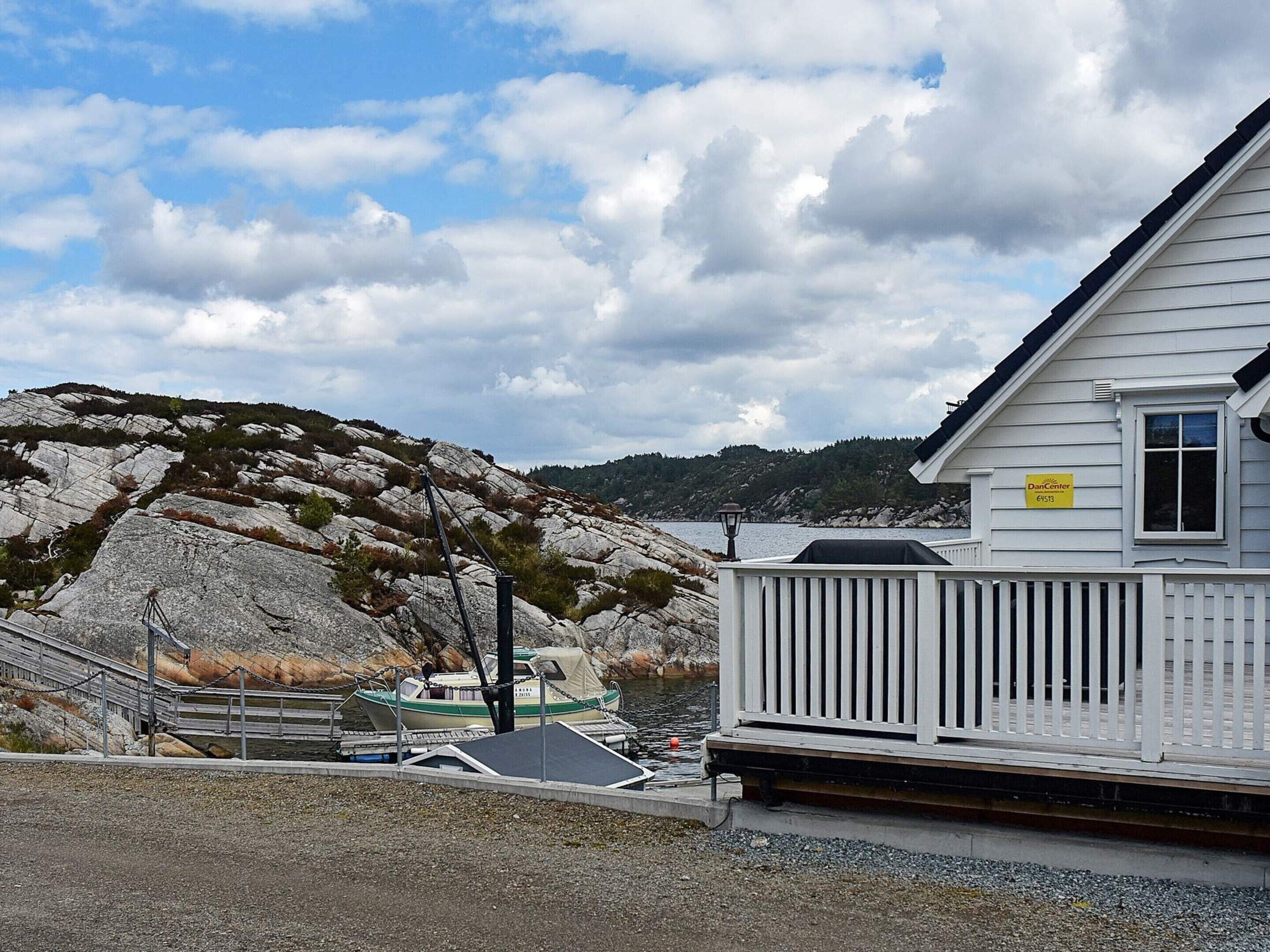 Un bâtiment situé sur la côte, avec une façade blanche et une zone aménagée en quai.
