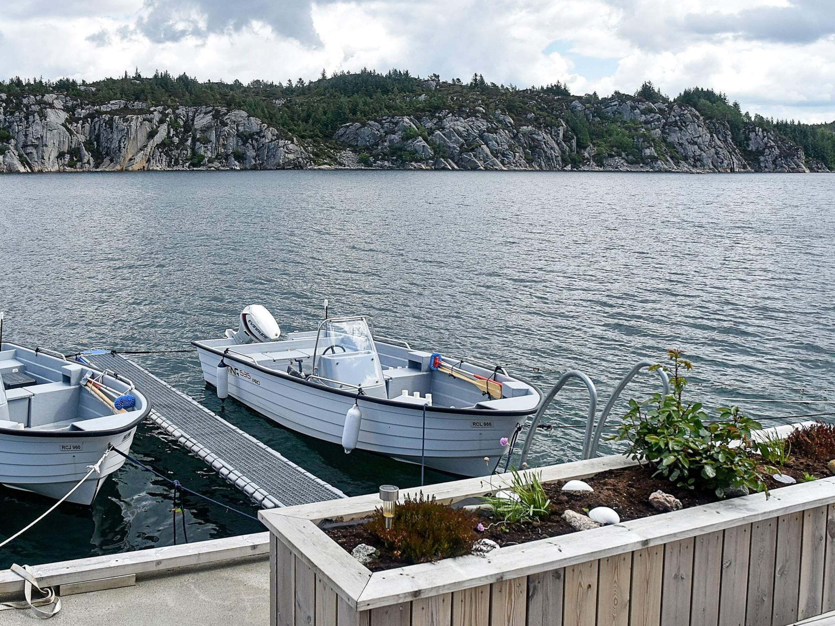 A dock with two boats, a rocky shoreline, and a clear sky.