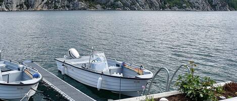 A dock with two boats, a rocky shoreline, and a clear sky.