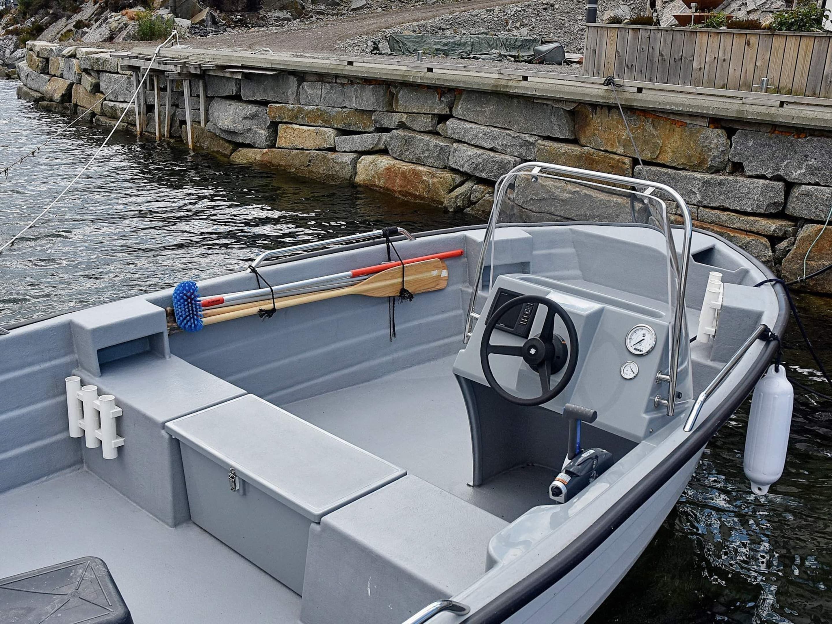 Un petit bateau à moteur était amarré à un quai en pierre. On pouvait y voir un cockpit dégagé, un volant et une rame.