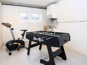 A foosball table with a magnetic system, an exercise bike, and a window with a view of a bridge.