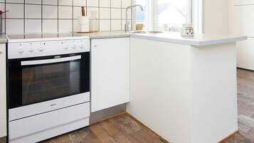 A kitchen with a built-in oven, white cabinets, a sink, and a window providing natural light.