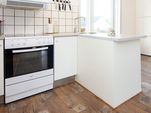 A kitchen with a built-in oven, white cabinets, a sink, and a window providing natural light.