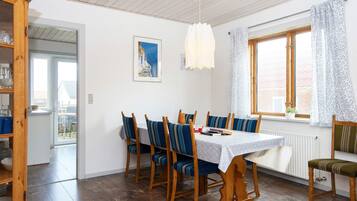 A dining area with a wooden table and chairs, a window with curtains, and a view of the outside.