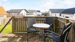 A wooden deck with a round table and four wicker chairs, surrounded by a wooden fence. - 8 Person Holiday Home in Thyboron-by Traum (Thyborøn)