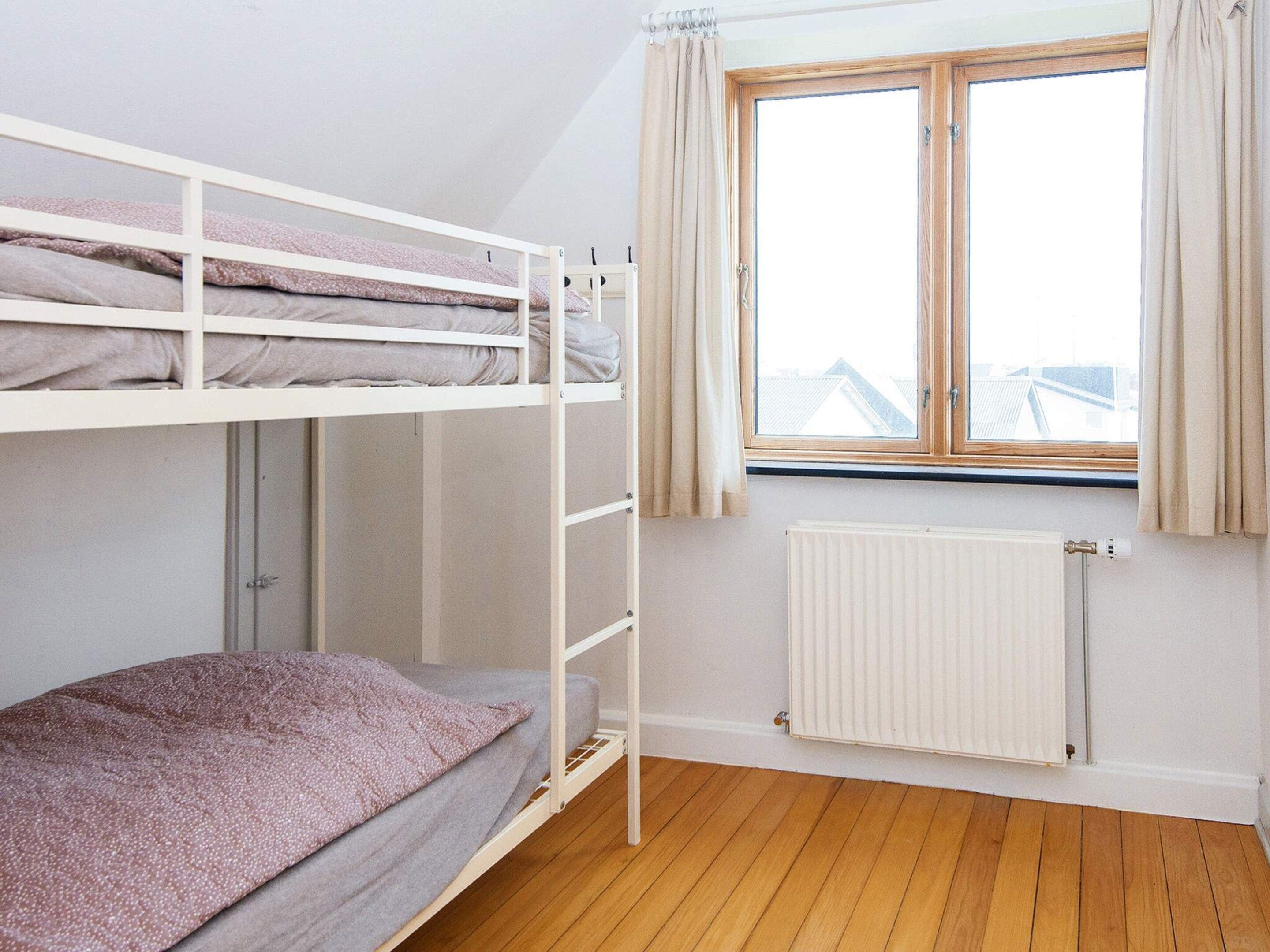 Kerrossängyllä varustettu huone, jossa on ikkuna ja patteri.