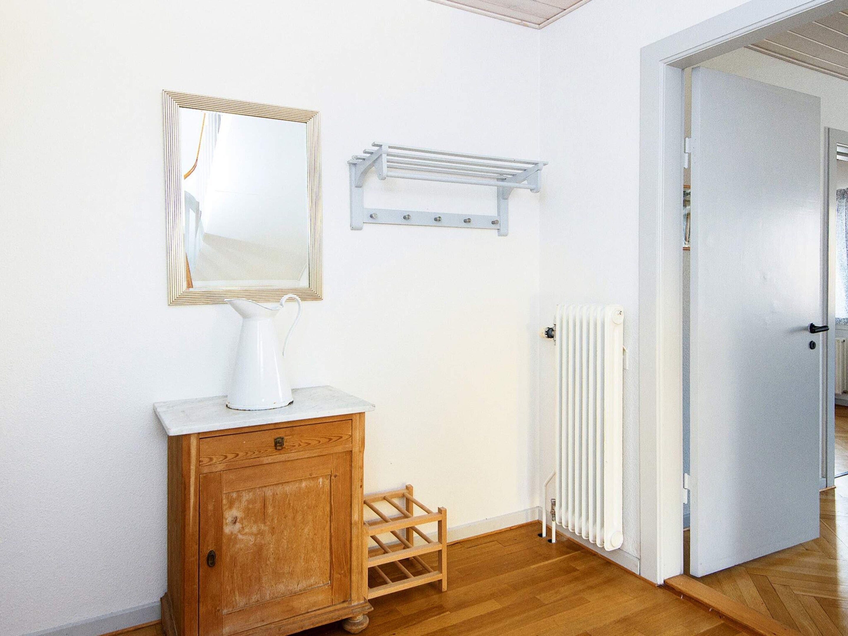 Habitació amb un armari de fusta, un radiador blanc i una porta que dona a una altra habitació.