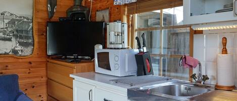 Una cuina compacta amb microones, cafetera i rentamics.