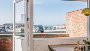 Ein Zimmer mit großem Fenster mit Blick auf einen Parkplatz und einen Strand.