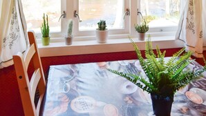 A room with a window, a table with a coffee-themed tablecloth, and several potted plants on the windowsill. - 8 Person Holiday Home in Lindesnes (Lindesnes)