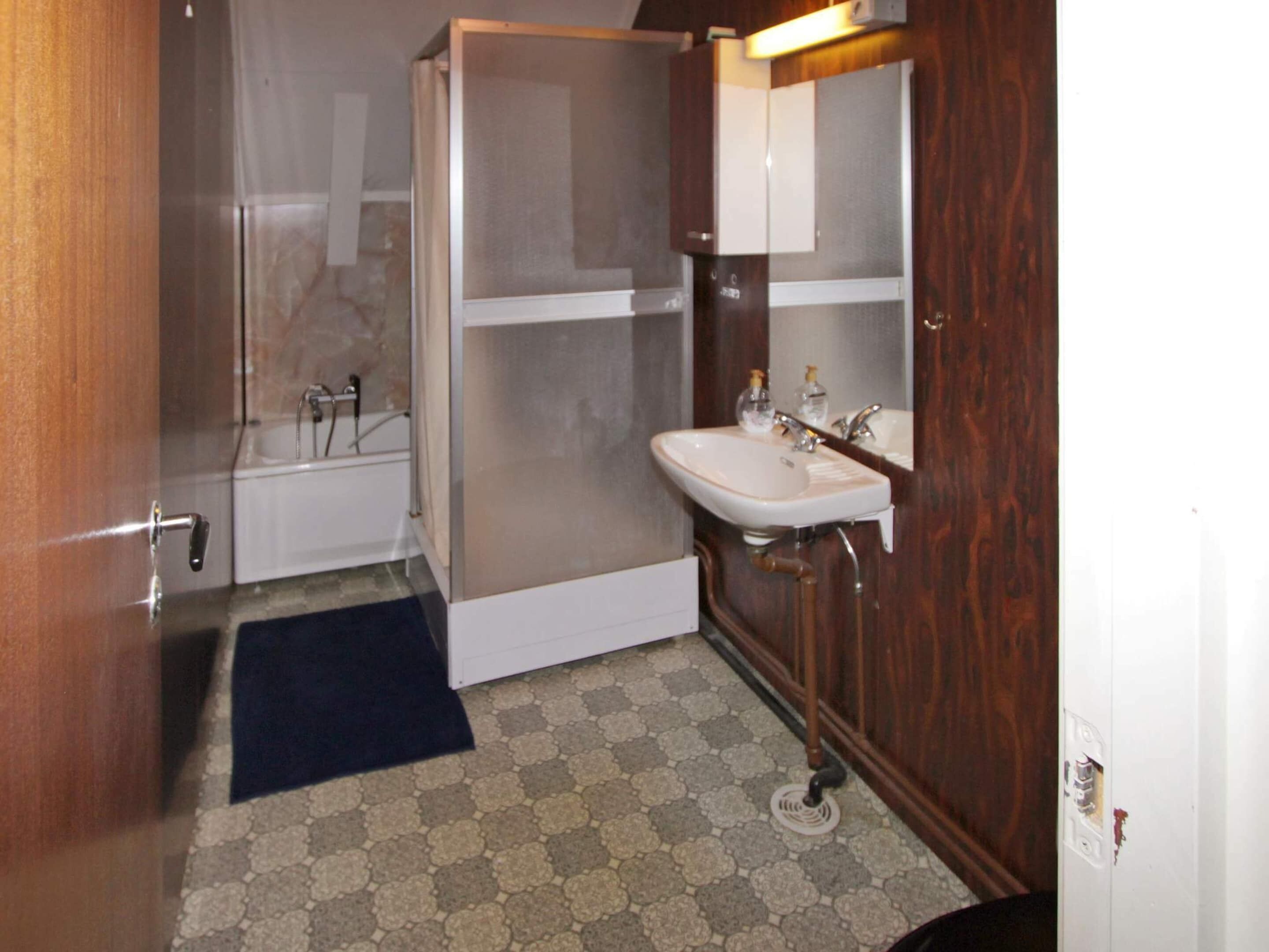 A compact bathroom with a shower, a sink, and a mirror.