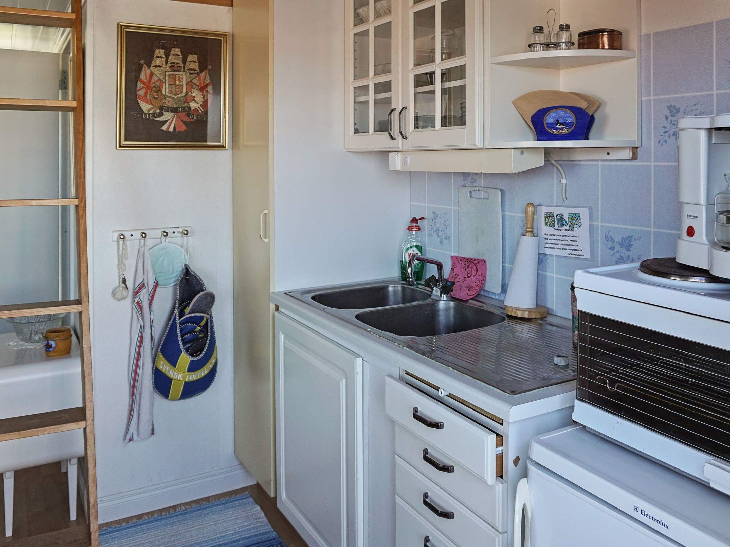 A kitchen with a sink, cabinets, a microwave, and a kettle.