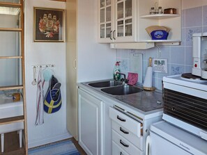 A kitchen with a sink, cabinets, a microwave, and a kettle.
