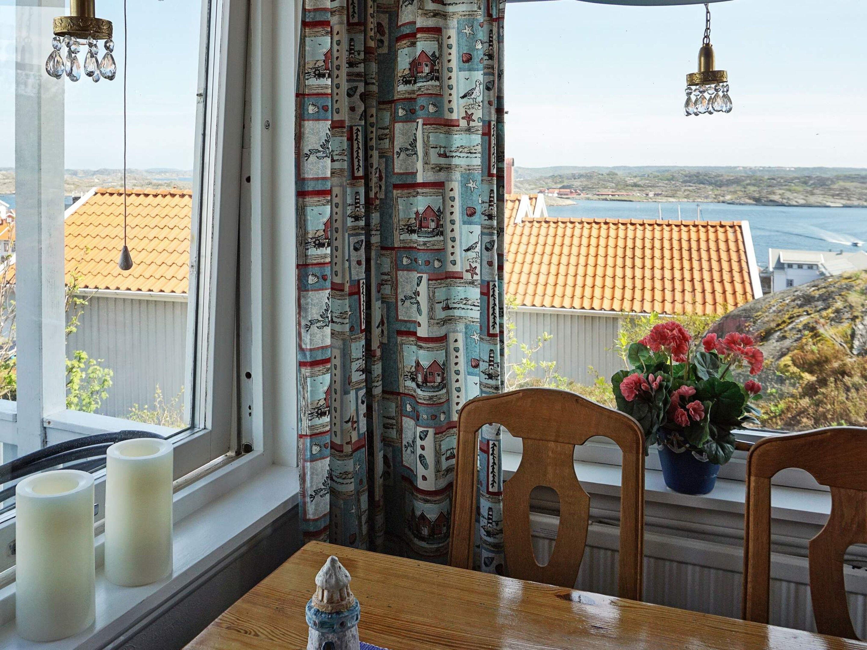 A room with a view of a coastal landscape, a table with candles, and a potted plant with flowers.