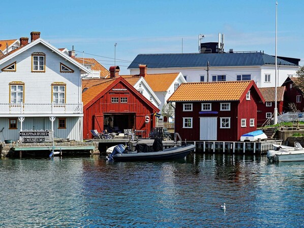 A waterfront scene with a museum sign, red and white buildings, and a dock with boats. - 3 Person Holiday Home in Gullholmen (Gullholmen)