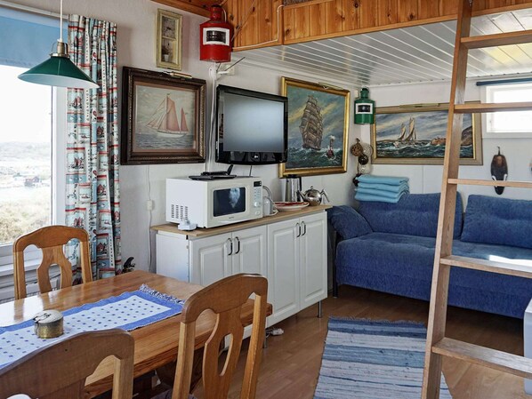 A compact living space with a dining area, a blue sofa, and a television. - 3 Person Holiday Home in Gullholmen (Gullholmen)