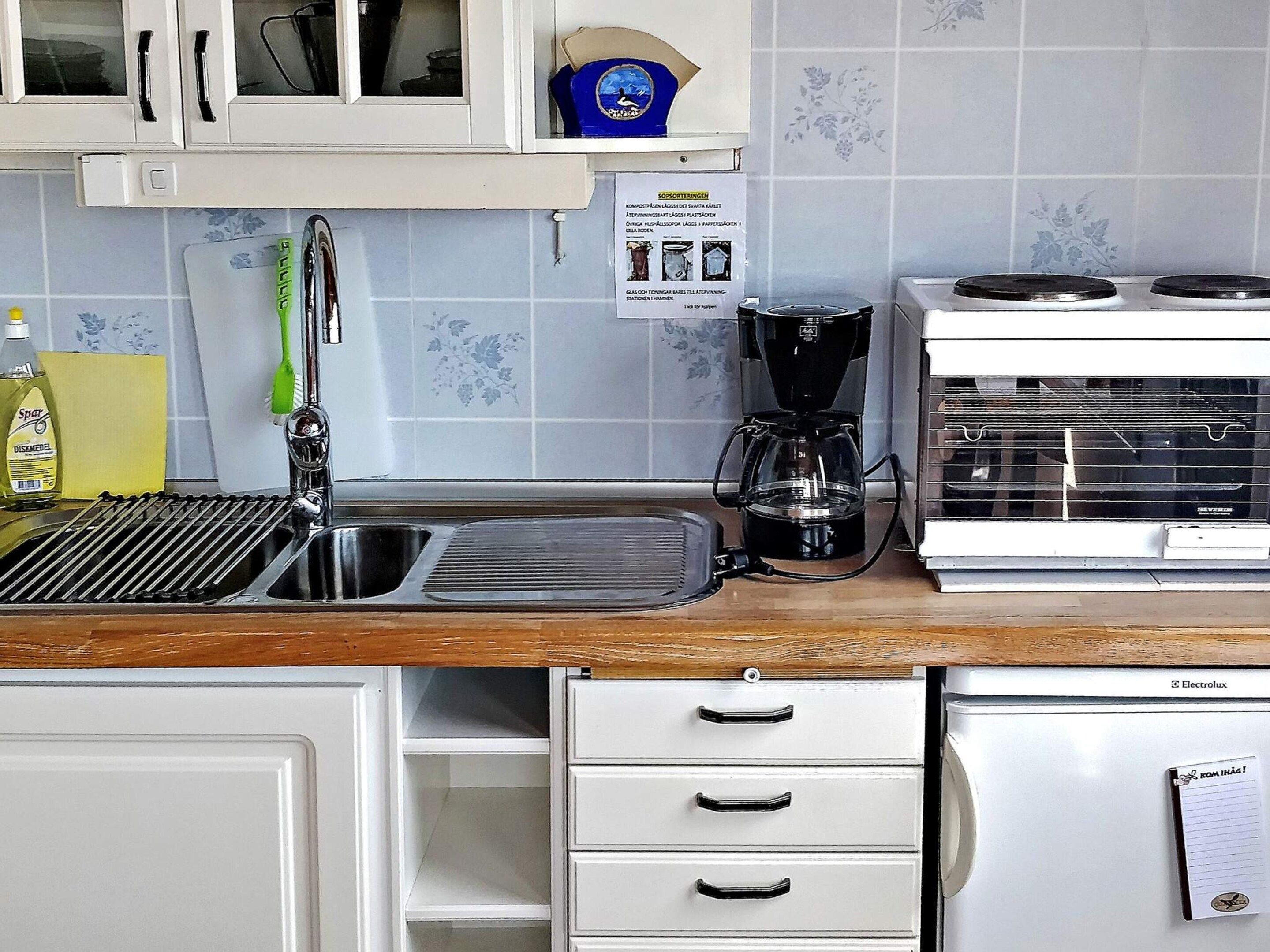 Una cucina con lavello, macchina del caffè e frigorifero.