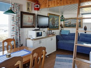 A compact living space with a dining area, a blue sofa, and a television.
