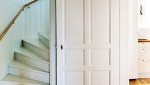A staircase with a wooden handrail leading to a white door with a handle. - Holiday Home in Gamleby (Gamleby)