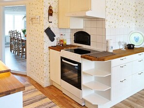 Una cucina con mobili bianchi, forno nero e piano di lavoro in legno.