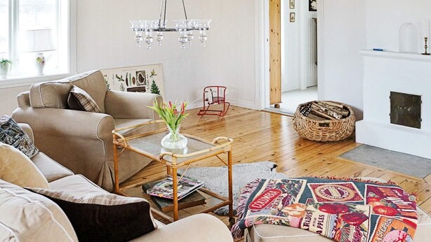 A living room with a sofa, a glass coffee table, a hanging light fixture, and a fireplace. - Holiday Home in Gamleby (Gamleby)