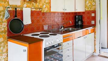 A kitchen with a stove, sink, and cabinets.