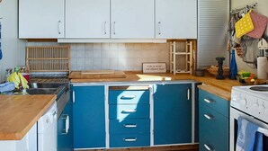 A kitchen with blue cabinets, a wooden countertop, a stove, and a sign that says "Life is short - eat dessert first!" - 5 Person Holiday Home in OS (Bjørnafjorden)