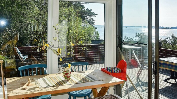 A wooden deck with a table and chairs, a bench, and a view of the water. - 5 Person Holiday Home in OS (Bjørnafjorden)