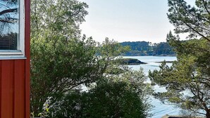 A view of a lake with a dock and a building with a red exterior. - 5 Person Holiday Home in OS (Bjørnafjorden)