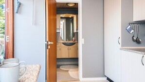 A modern kitchen with a wooden ceiling, a sink with a mirror, and a countertop with mugs. - 4 Person Holiday Home in Juelsminde (Horsens)
