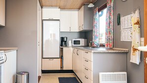 A compact kitchen with a refrigerator, microwave, coffee maker, and a small air conditioner. - 4 Person Holiday Home in Juelsminde (Horsens)