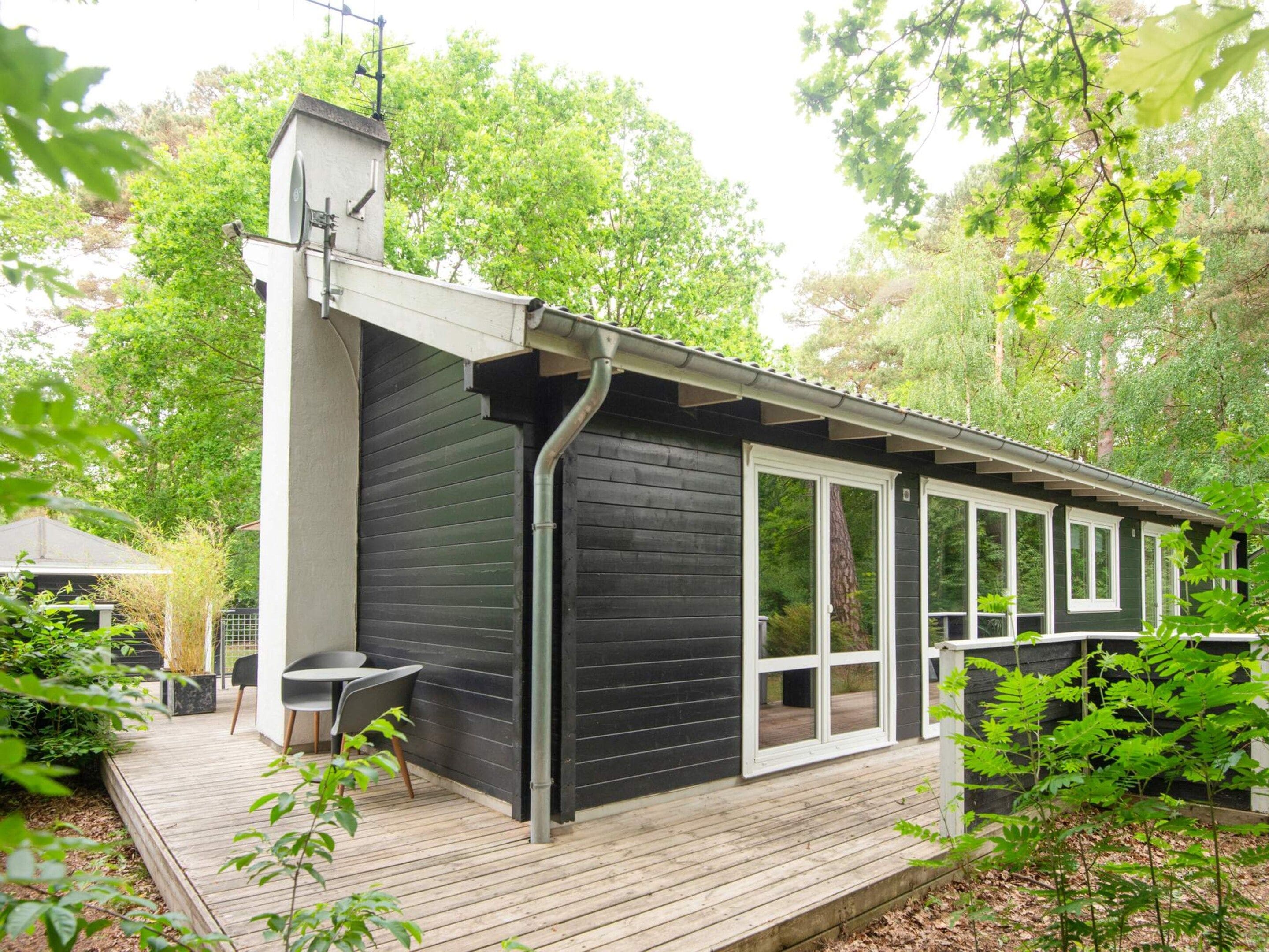 Et moderne hus med en terrasse, store vinduer og en skorsten.
