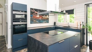 A modern kitchen with a central island, built-in ovens, and a large window. - 5 Star Holiday Home in Ronde (Ronde)
