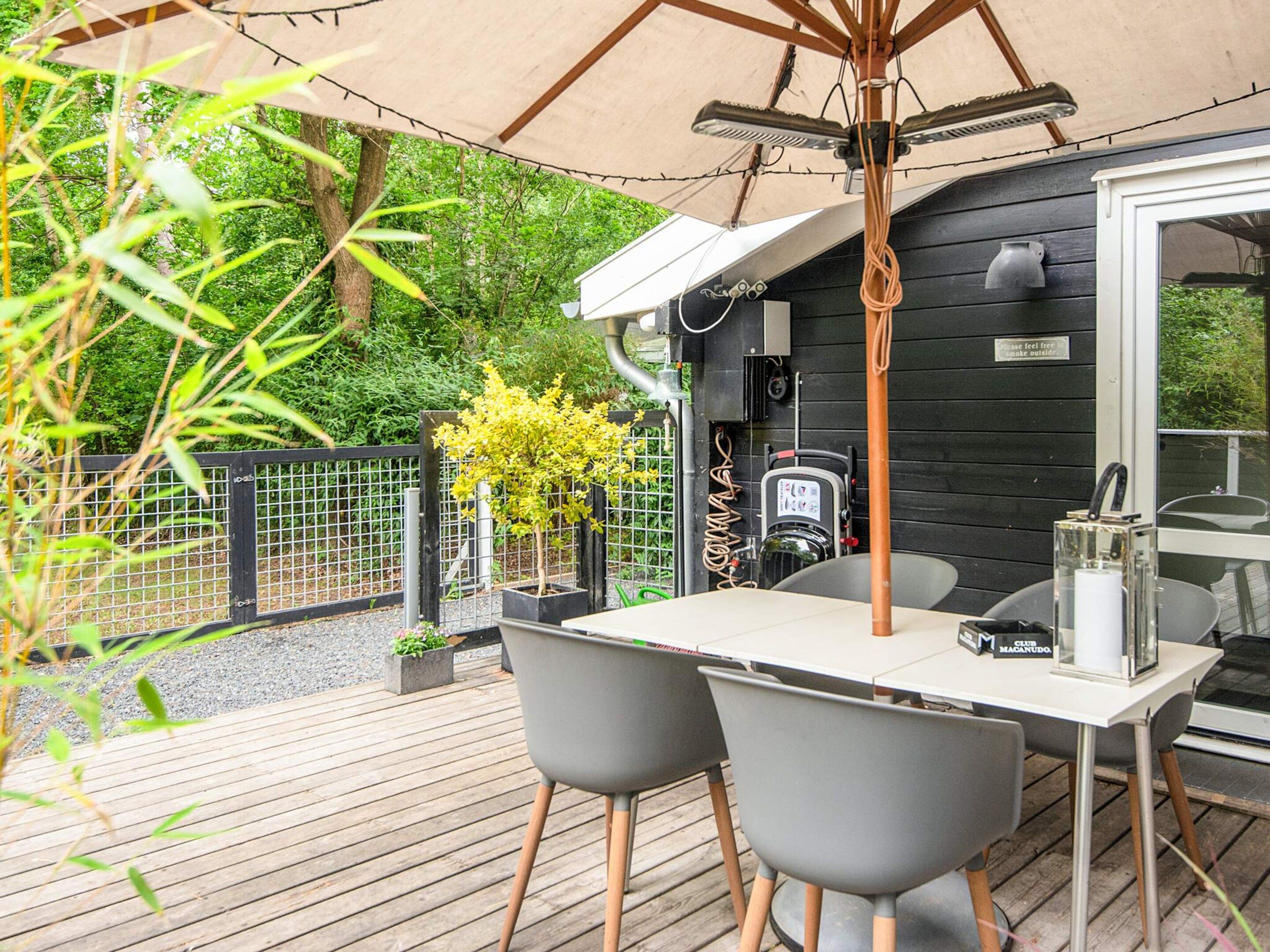 An outdoor patio with a table and chairs, a barbecue grill, and a pergola with string lights.