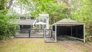 A fenced backyard with a covered outdoor seating area, a building with a tiled roof, and a shed. - 5 Star Holiday Home in Ronde (Ronde)