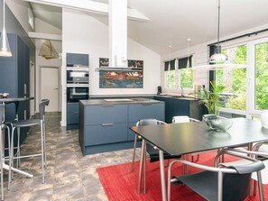 A modern kitchen with a central island, bar stools, and a dining table with chairs.