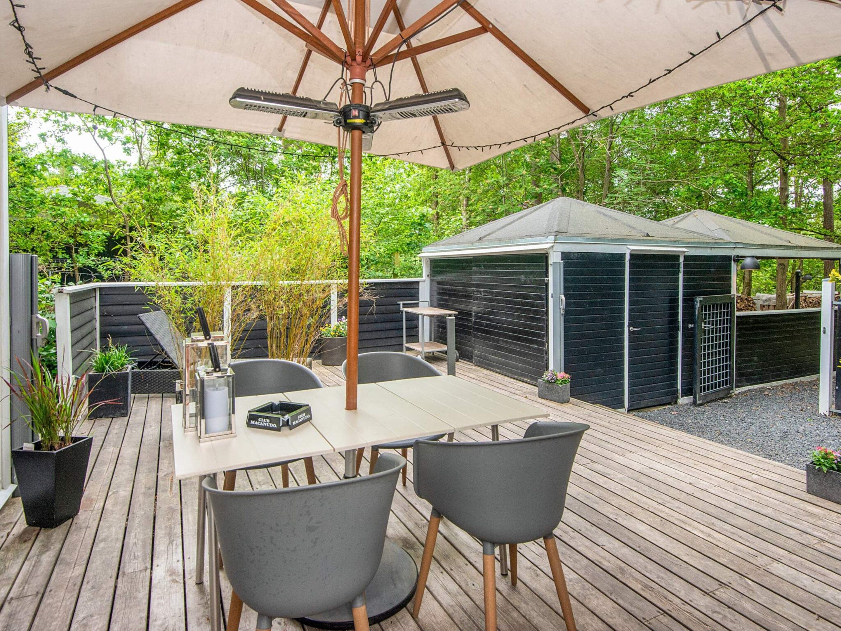 Eine Terrasse im Freien mit Tisch und Stühlen, einem überdachten Bereich und einem Geräteschuppen.