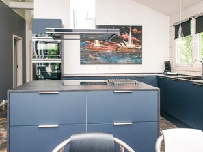 Una cucina moderna con una grande isola, una macchina da caffè e una finestra vista verde.