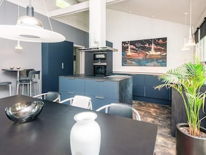 Uma cozinha moderna com ilha central, iluminação pendente e uma grande pintura na parede.