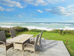 A deck with wicker furniture overlooking the ocean.